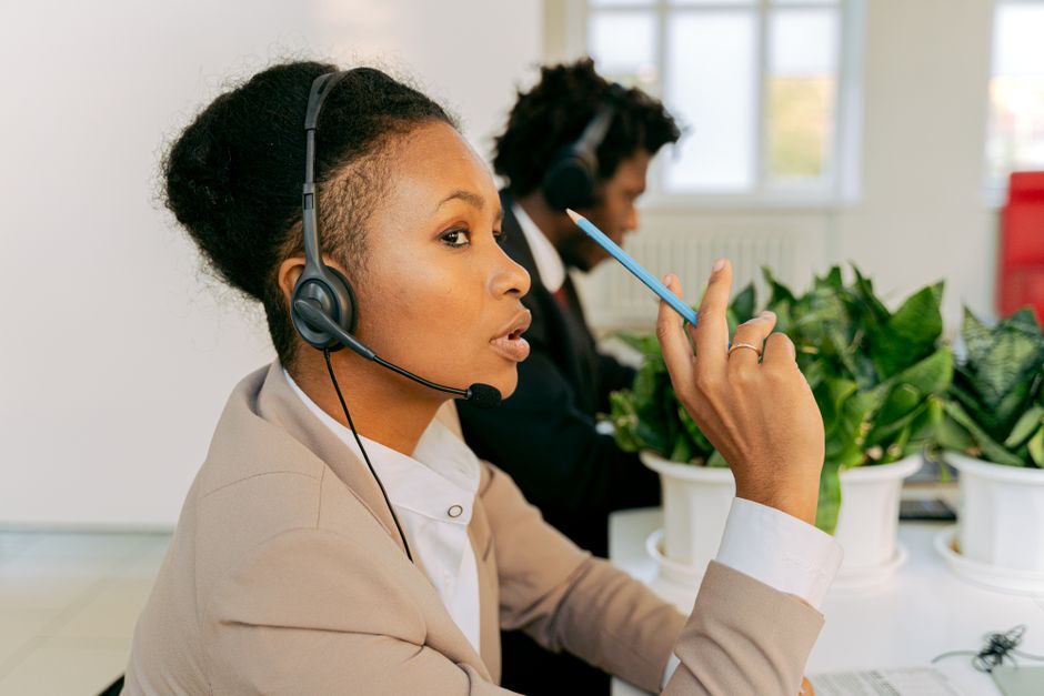 Two call center agents focused on customer service, wearing headsets in an office.