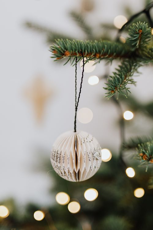 Free Close-up of a paper Christmas ornament with lights on a decorated tree branch. Stock Photo
