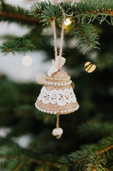 特写镜头捕捉了悬挂在节日松树枝上的手工钟形装饰品，烘托出节日气氛