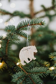 圣诞树树枝上悬挂的木熊装饰品特写，灯光温暖