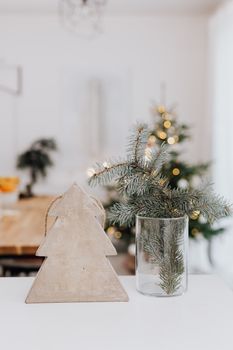 A modern Christmas scene featuring a wooden tree and vase with fir branches.