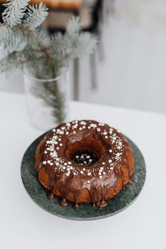 Mouthwatering chocolate ring cake with drizzle and sprinkles on a stand, perfect as a festive dessert.