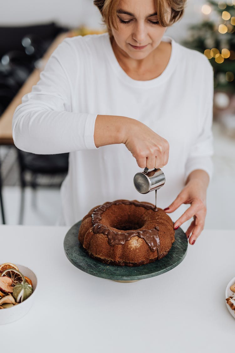 Woman Pouring Hot Chocolate On Bundt Cake