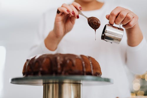Free Person Decorating Cake with Chocolate Stock Photo
