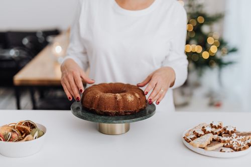 Free Woman prepares bundt cake for holiday celebration with Christmas decor. Stock Photo