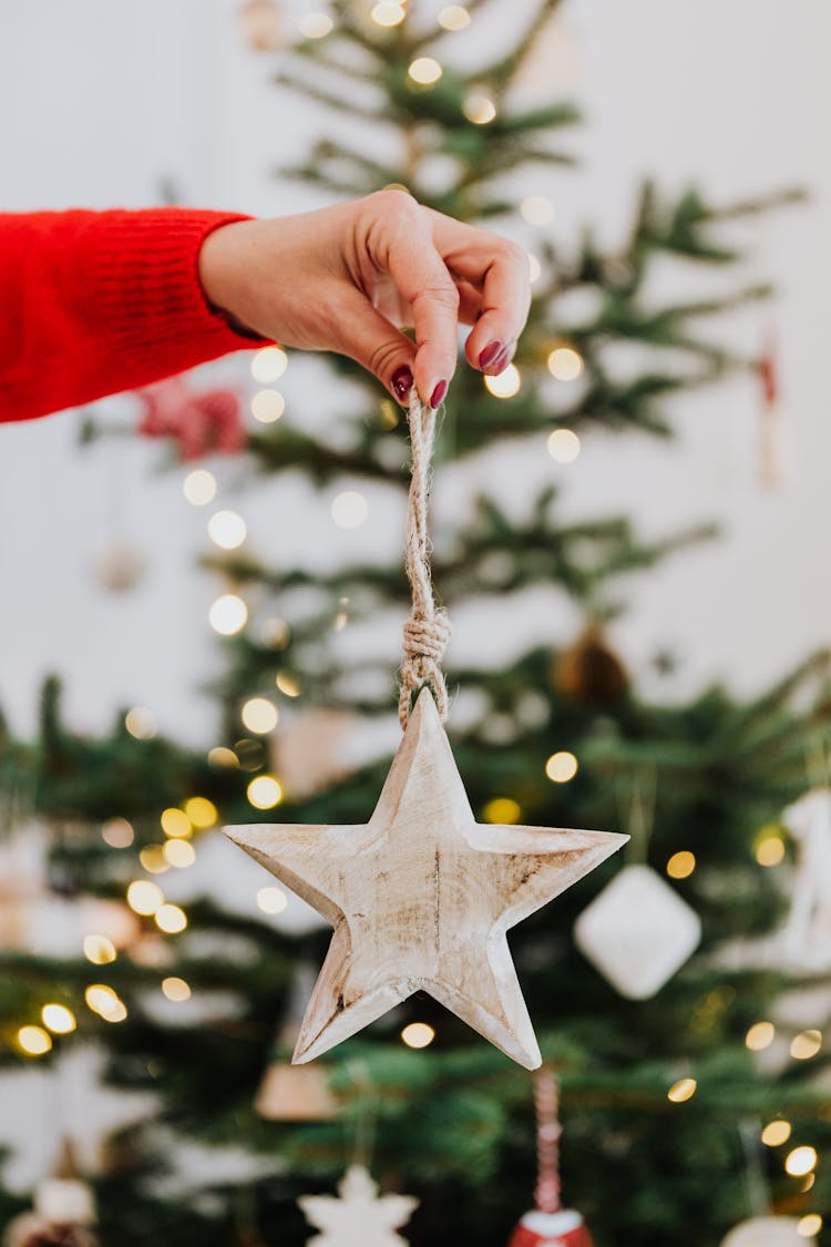 A Person Holding A Wooden Star Christmas Ornament