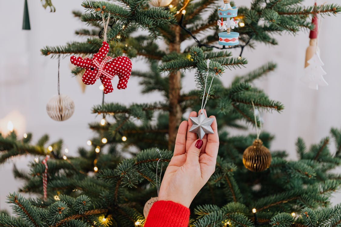 Person Holding a Silver Star Christmas Ornament