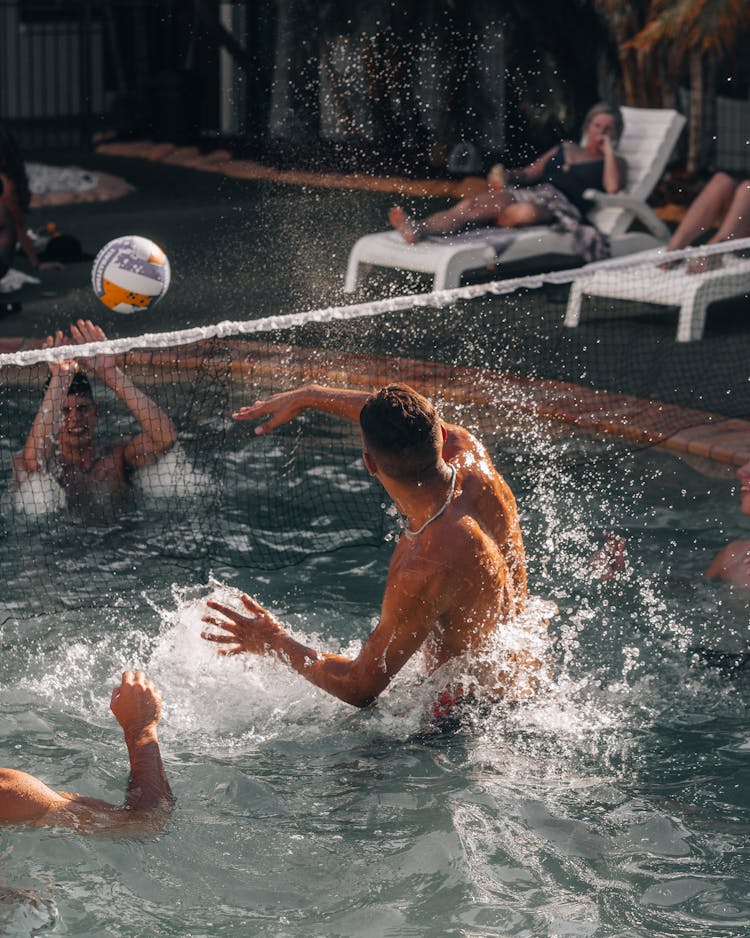 A Group Of People Playing Water Volleyball In The Pool