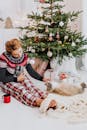 一名妇女和她的猫在装饰好的圣诞树和礼物旁，享受着舒适的圣诞节