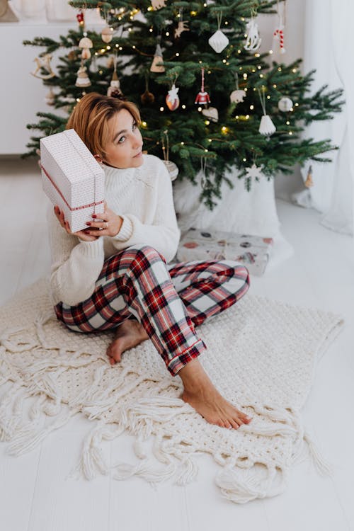 Girl in White Sweater Sitting on the Floor while Holding a Gift Box