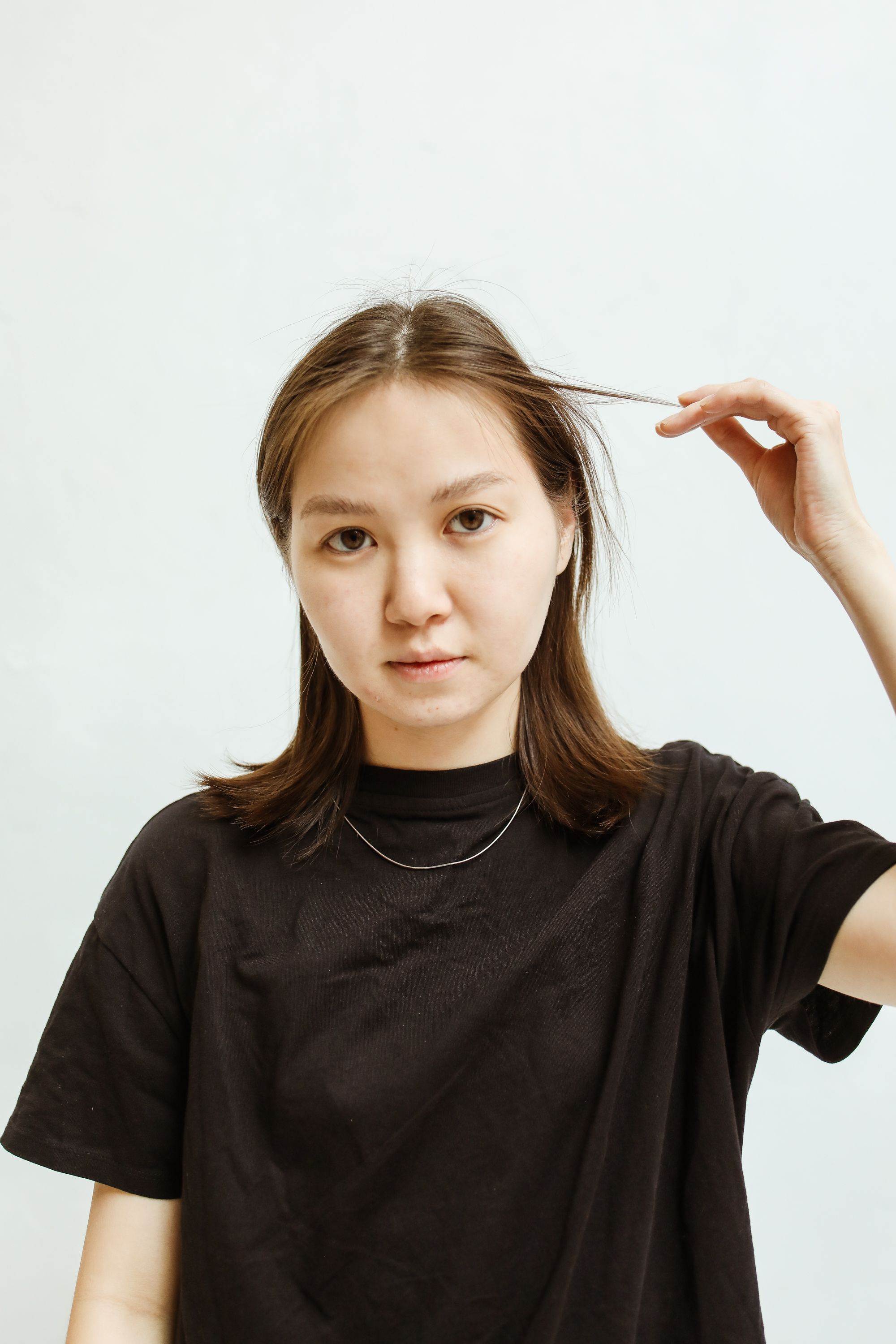 一位年轻女子身穿黑色衬衫，在浅色背景下拍摄的特写肖像
