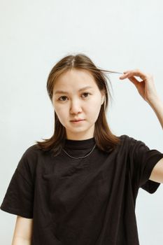 一位年轻女子身穿黑色衬衫，在浅色背景下拍摄的特写肖像