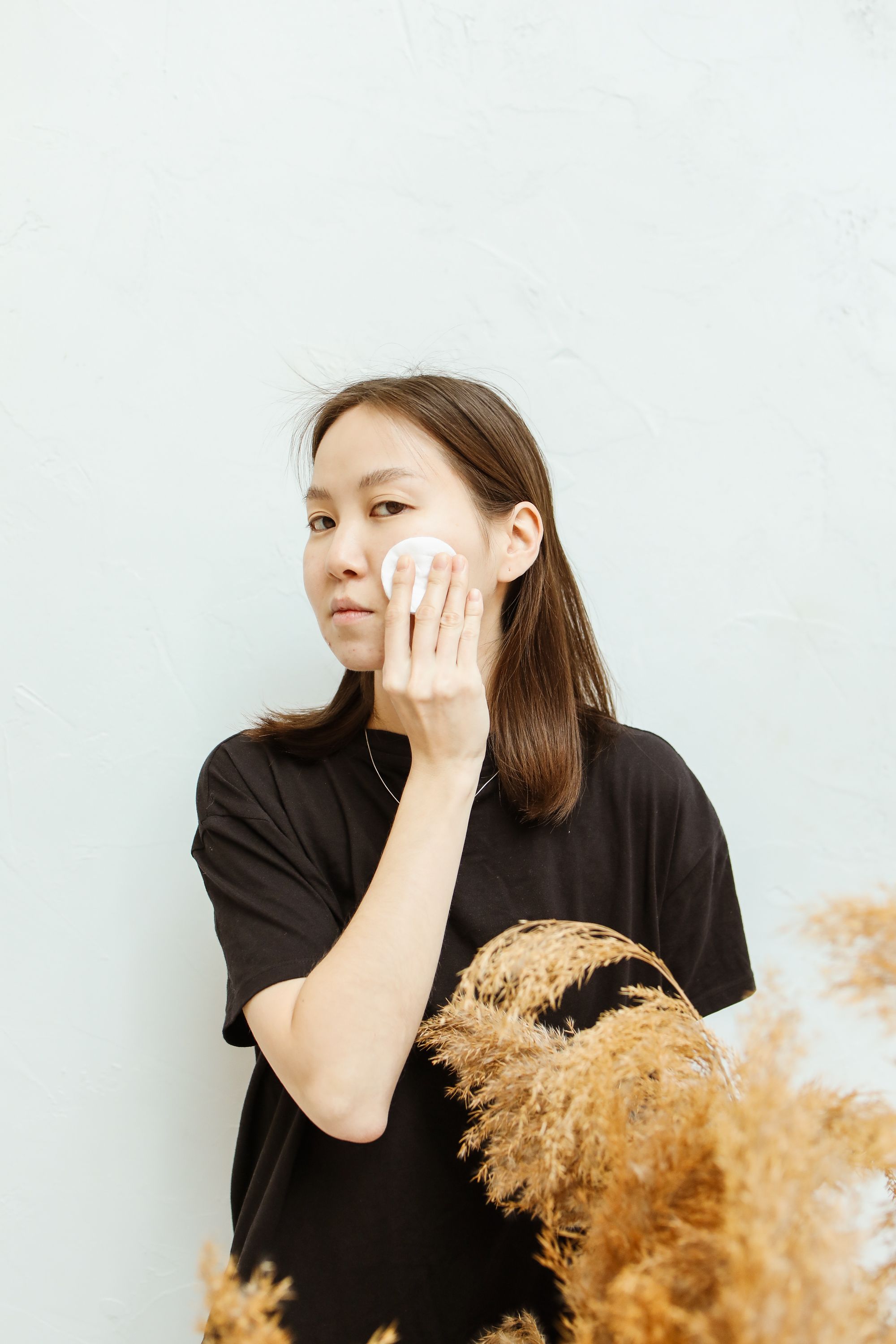 a woman wiping her face with a cotton pad
