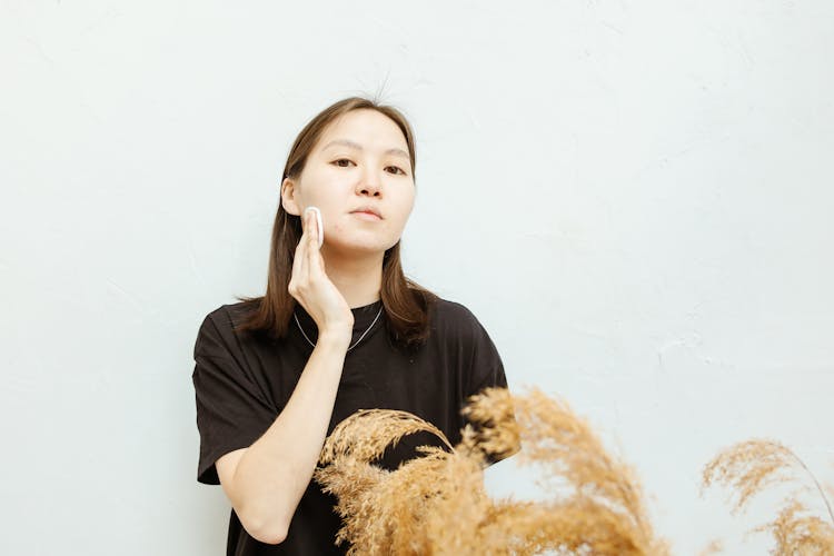 A Woman Wiping Her Face With A Cotton Pad