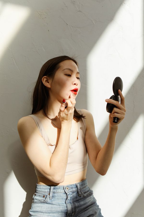Woman applying red lipstick with a compact mirror
