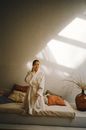 Woman in White Robe Sitting on Bed