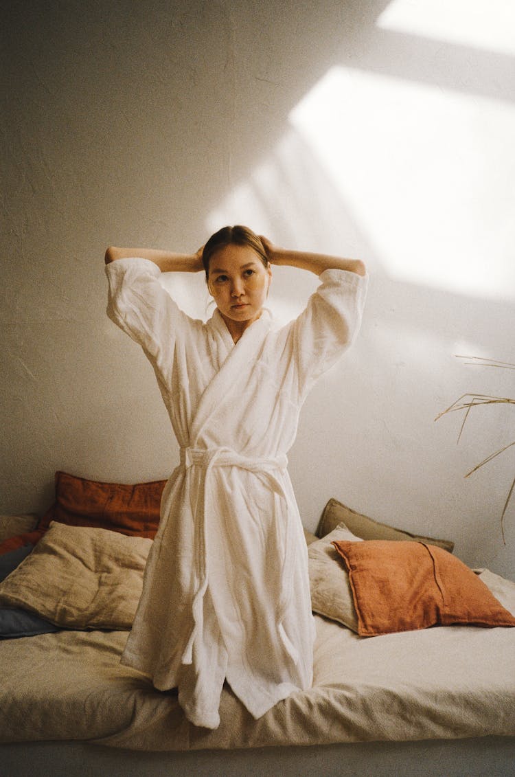 A Woman Wearing A Bathrobe Tying Her Hair