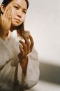 一位年轻女子在自然光线下穿着浴衣，正在涂抹护肤保湿霜