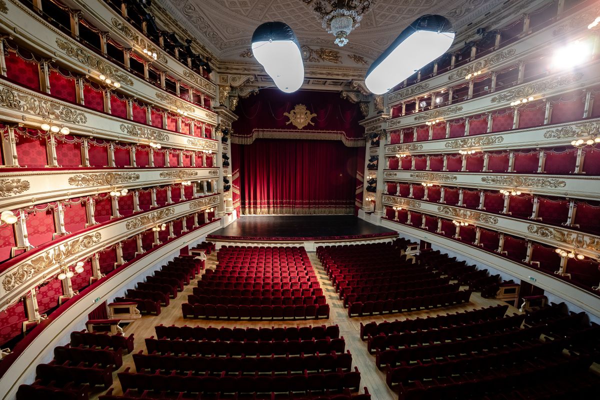 Ornate interior of a historic Italian opera house with gilded boxes and chandelier
