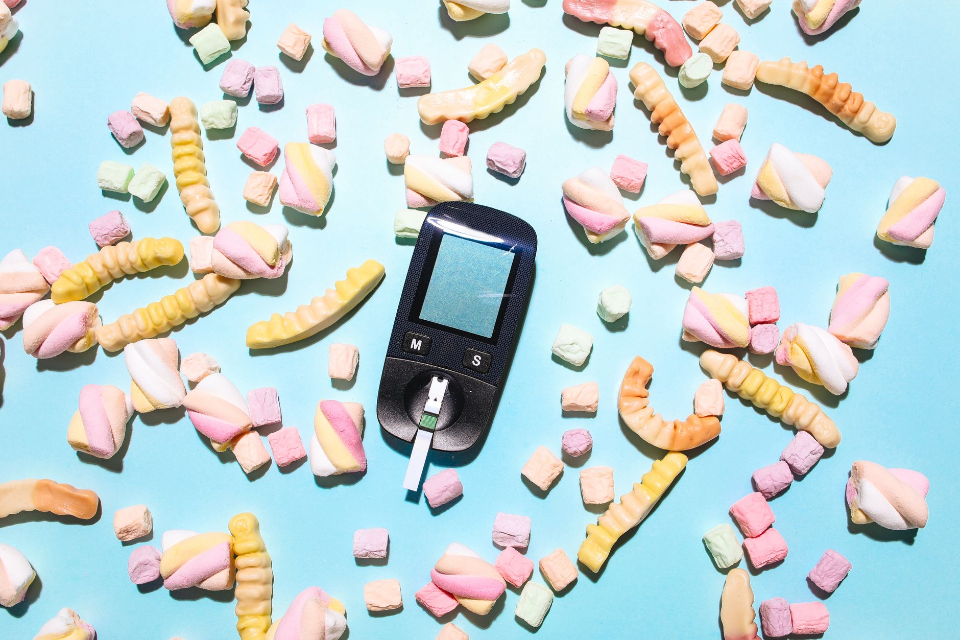 diabetes superstar foods - Colorful arrangement of candies and a glucose meter illustrating diabetes management.