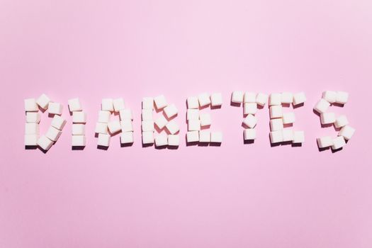 粉色表面上，“糖尿病”一词由方糖拼成，凸显了健康问题