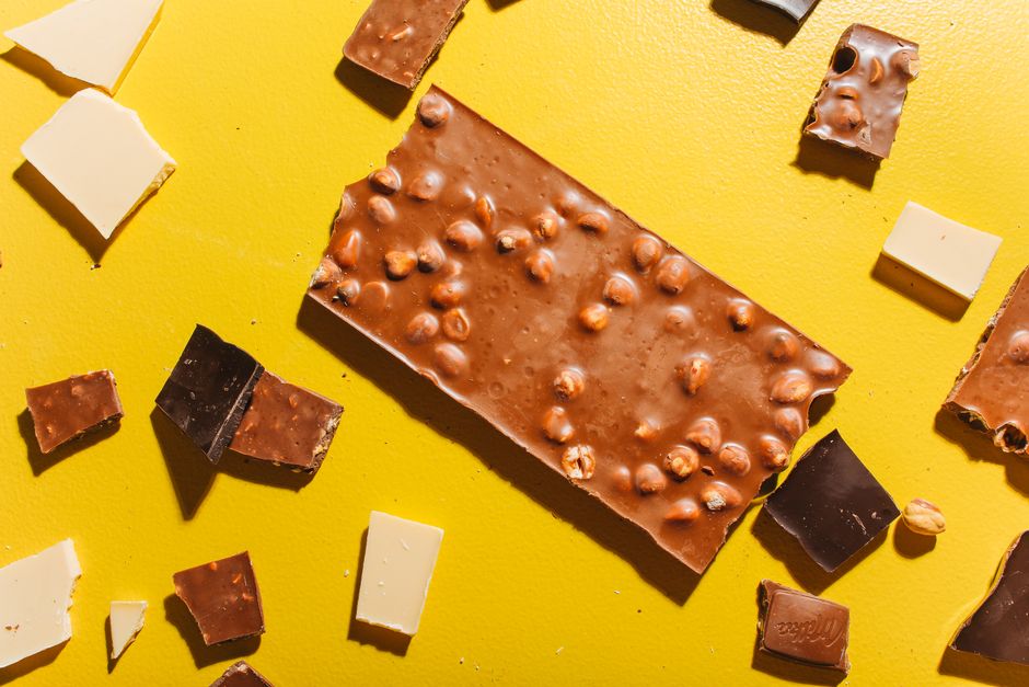A variety of chocolate pieces on a bright yellow backdrop, showcasing textures and colors.