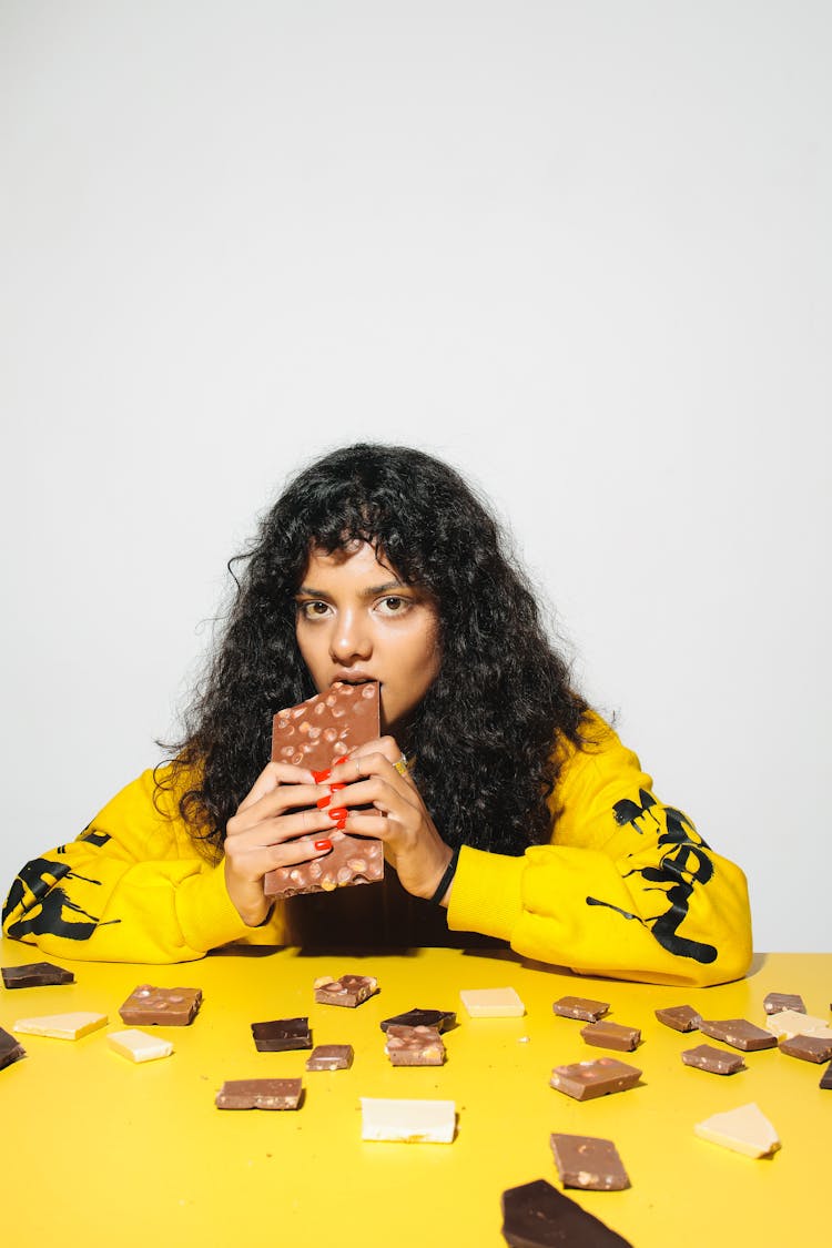 Curly-Haired Woman Eating A Chocolate Bar
