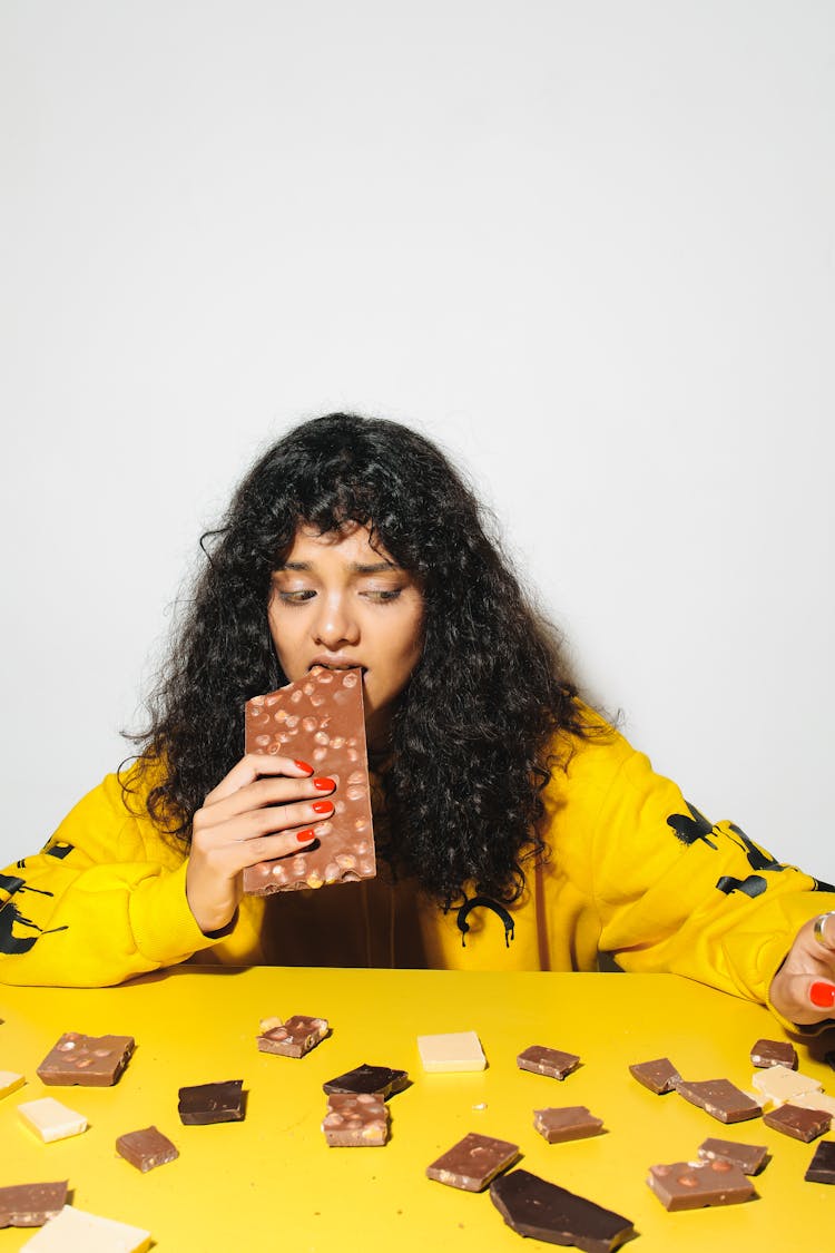 Curly-Haired Woman Eating A Chocolate Bar