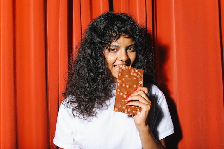 Curly-Haired Woman Eating A Chocolate Bar