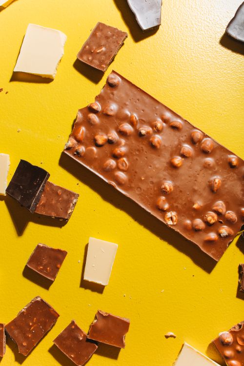 Free Close-up of mixed chocolate types on a bright yellow background, featuring milk and dark varieties. Stock Photo