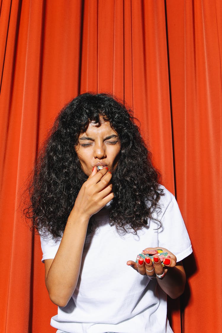 Woman In White Shirt Eating Candies