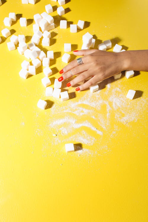 Free Close-Up Shot of Person Holding Sugar Cubes on Yellow Surface Stock Photo