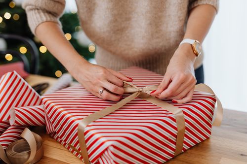 Free Hands tying a bow on a red and white striped gift box, perfect for holiday content. Stock Photo