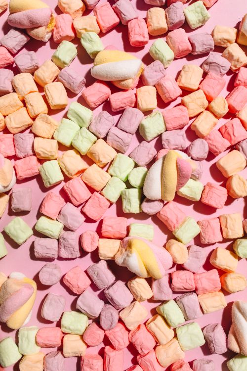 Free Vivid array of pastel-colored marshmallows scattered across a light pink backdrop. Stock Photo