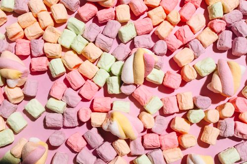 Free Vibrant pastel marshmallows scattered on a pink surface, creating a soft, playful appearance. Stock Photo