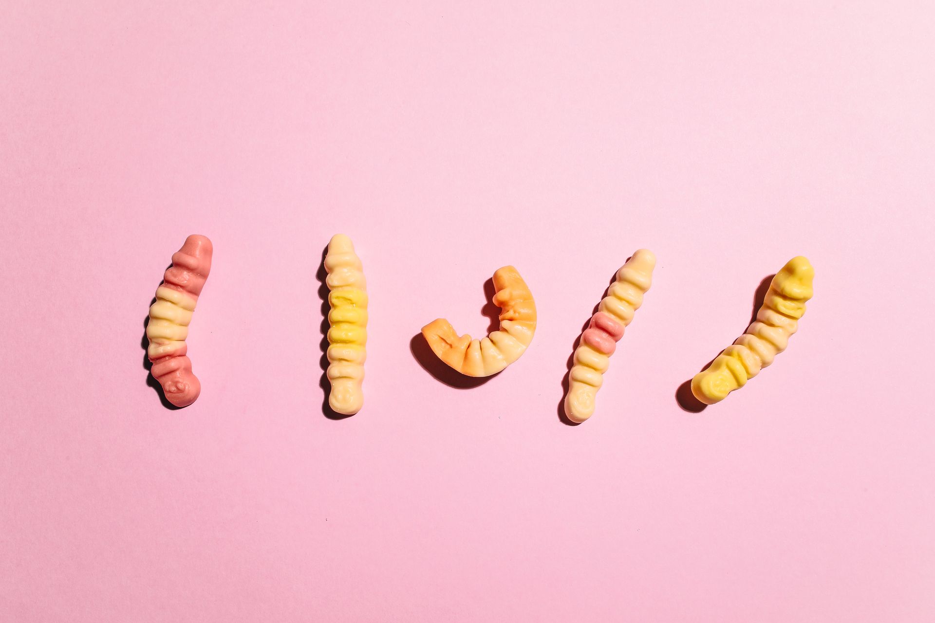Close-Up Shot of Gummy Worms on Pink Surface