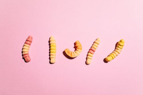 Free Colorful gummy worms arranged on a soft pink surface, ideal for candy-themed projects. Stock Photo