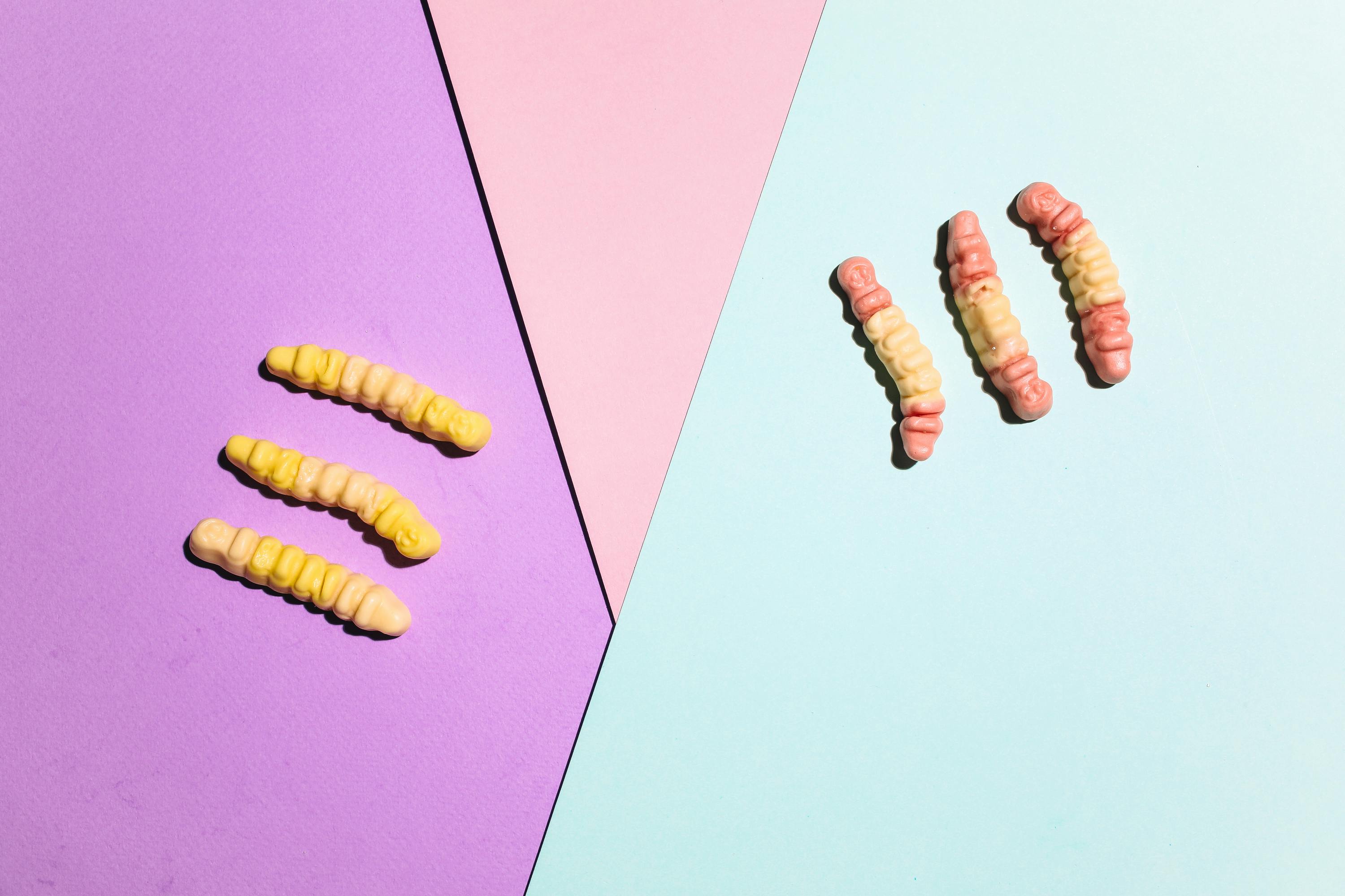 软糖蠕虫在彩色纸质背景上排列得很有趣，非常适合用作糖果图像