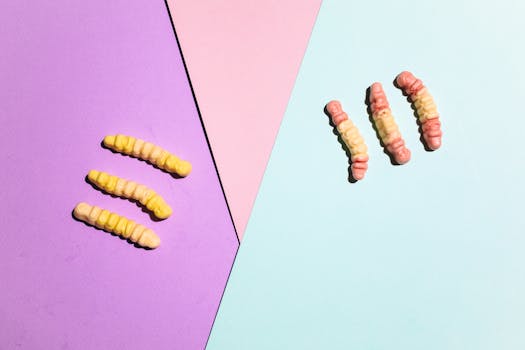 软糖蠕虫在彩色纸质背景上排列得很有趣，非常适合用作糖果图像
