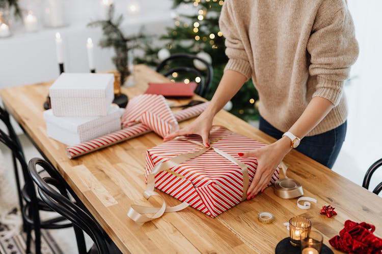 Woman Packing Christmas Presents On Table