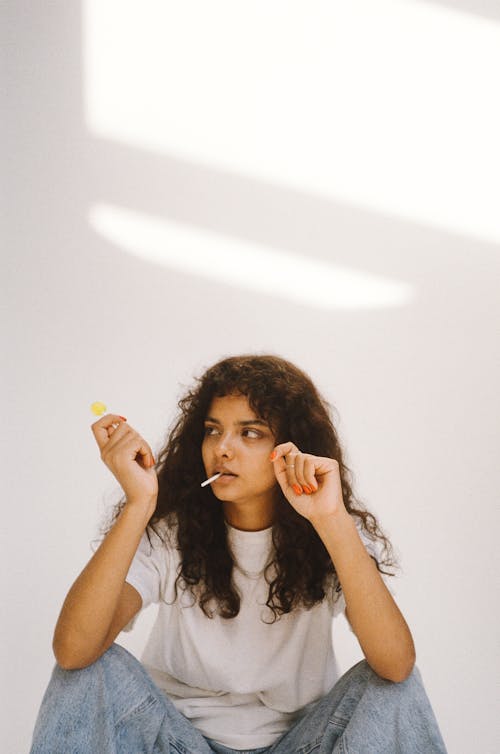 Curly-Haired Woman Eating Lollipop