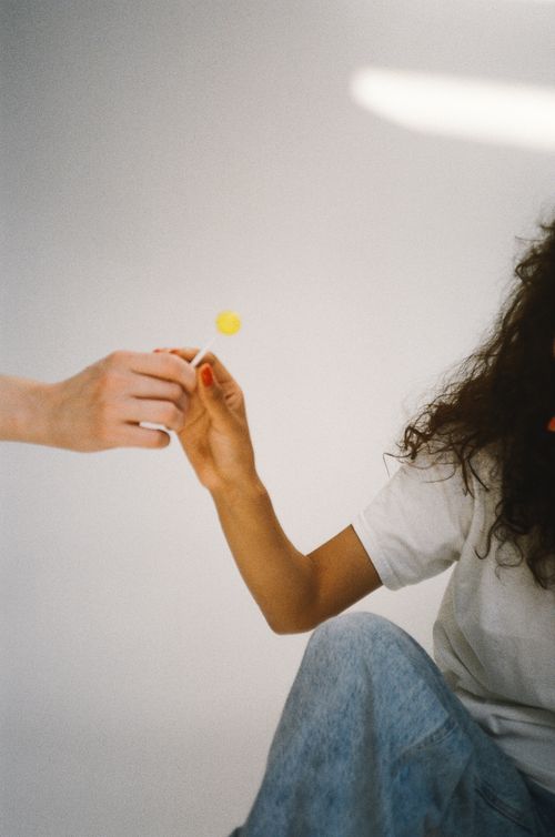 Free Close-up of two people exchanging a lollipop, symbolizing sharing and connection. Stock Photo