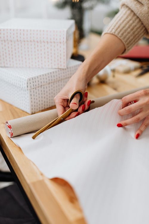 Free Close-up of hands wrapping gifts with scissors, festive preparation indoors. Stock Photo
