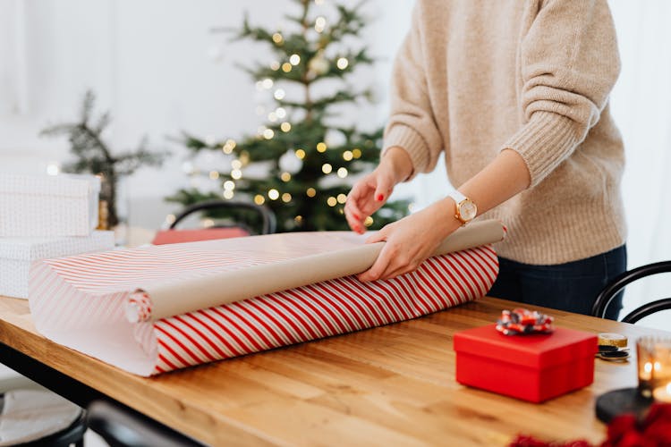 Person In Beige Sweater Wrapping A Gift