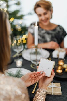 在节日餐桌上，两名妇女交换了带有圣诞装饰的项链礼物，周围烛光闪烁