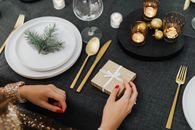 节日餐桌上，小礼品盒、蜡烛和金色餐具的特写，营造出温暖的氛围