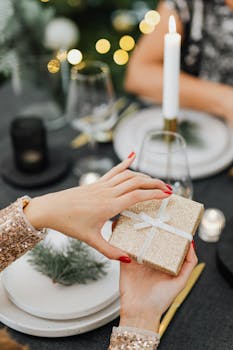 烛光餐桌上，两名女子交换闪闪发光的圣诞礼物的特写镜头