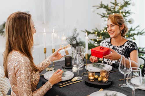 Free Friends Exchanging Christmas Gifts at Dinner Stock Photo
