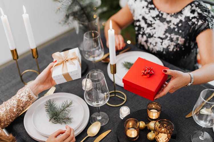 Friends Exchanging Christmas Gifts At Dinner