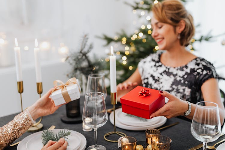 Friends Exchanging Christmas Gifts At Dinner